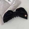 Detailed macro view of a elegant black satin bow hair banana clip featuring a gold charm - Black