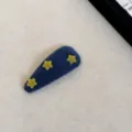 Gros plan détaillé d'une pince à cheveux en velours bleu avec de jolis motifs d'étoiles jaunes - Pentagramme / Bleu foncé