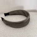 Vue détaillée rapprochée de la texture élégante du tissu plissé vert olive sur un large serre-tête - Vert