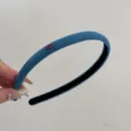 Detail view showing the soft texture of a thin blue suede headband with Love badge - Light Blue