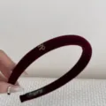 Close-up detail of a retro burgundy velvet headband featuring a small gold metallic bow - Red Bow Style / Red