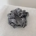Detailopname van een zwart-wit geruite scrunchie met een handgemaakt label - Zwart-wit Rasterstijl / Zwart-wit geruit