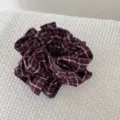 Close-up van een vintage bordeauxrode stoffen scrunchie met witte ruitpatronen op stof - Rode Ruit Stijl / Rood Geblokt