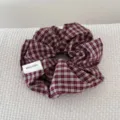 Detailed macro view of a burgundy checkered retro fabric scrunchie with hand made tag - Red Plaid Scrunchie