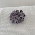 Detailed view of a purple floral scrunchie hair tie on white textured fabric background - Purple Hair Scrunchie (FJ83662)