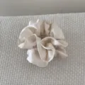 Détail d'un chouchou en satin plissé double couche crème sur fond de tissu texturé - Beige