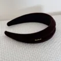 Primo piano di un cerchietto imbottito in velluto retrò con elegante scritta dorata handmade. - Stile Scritte / Marrone scuro