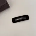 Gros plan d'une pince à cheveux rectangulaire en velours marron foncé sur fond blanc - Carré / Café Foncé