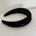Dettaglio ravvicinato di un cerchietto in velluto nero con scritta in metallo dorato - Stile Scritte / Nero