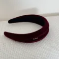 Dettaglio ravvicinato di un cerchietto in velluto bordeaux imbottito con targhetta Handmade - Stile Scritte / Rosso