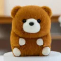 Süßer kugelförmiger brauner Plüsch-Teddybär, der auf einem weißen Sockel steht - Braunbär