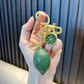 Realistic green lemon keychain with textured charm and gold-toned metal hardware. - Lemon Green
