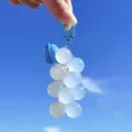Cute blue resin grape cluster keychain accessory for car keys and bags held against blue sky - Color-Changing Grape / Blue