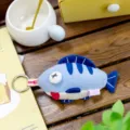 Detailed macro view of a cute blue plush fish keychain with quirky cross-eye and tongue - Fish Pattern