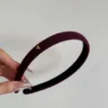 Vista dettagliata di un cerchietto in maglia bordeaux con un piccolo cuore dorato. - Cerchietto con Cuore / Largo 1.5cm / Borgogna
