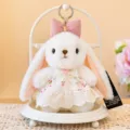 Witte pluche konijnenpop met roze strik en bloemenkantjurk op een witte standaard. - Lily Konijnenhanger (Beige)
