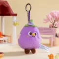 Macro view of cute purple eggplant plush doll keychain featuring a green floral stem detail - Eggplant