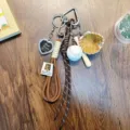 Sports-themed keychain with mini baseball, glove, bat, and brown braided cords. - Coffee