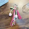 Handmade colorful woven heart bag charm featuring a pink tassel and fabric tulip flowers - Rose Red