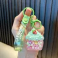 Cute cupcake-shaped keychain featuring colorful jelly beans and a strawberry charm on a green strap - Green