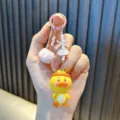 Süßer gelber Enten-Handyanhänger mit bunten Perlen, rosa Bommel und Schleifen-Detail - Rosa