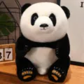 Realistic black and white panda plush toy sitting on a wooden desk in a cozy home setting - Floral / 50cm