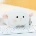 Adorably soft white fluffy lamb plush toy variant resting on a computer keyboard - Aries