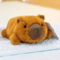Miniature brown capybara plush toy animal lying on a white desktop computer keyboard - Capybara