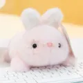 Adorable mini pink plush bunny toy resting on a white keyboard with soft warm lighting - Pink Rabbit