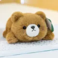 Adorable brown plush bear toy in crawling pose on white keyboard, palm size - Brown Bear
