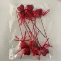 Close-up of red glitter heart picks with ribbons inside a clear plastic storage bag. - 10 Pcs/Set / Red