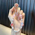 Handmade beaded phone charm featuring colorful flowers and pearls held by a hand - Red