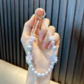 Elegant beaded flower phone strap with light blue pearls and translucent floral accents. - Blue