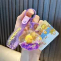 Purple acrylic shell keychain featuring a yellow duck and sparkling quicksand oil - Purple