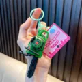 Miniature green vibrating pull-string chainsaw toy keychain shown held in hand - Green