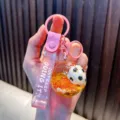 Sparkly pink football quicksand keychain with Just Keep Doing It printed strap variant - Pink