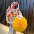 Colorful iridescent beaded keychain featuring a fluffy yellow pom-pom and heart charm - Yellow (Random Beads Tag)