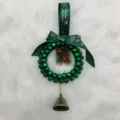 Close-up detail of a handmade green bell Christmas wreath with ribbon and pinecone - Diameter approx 12cm / Green
