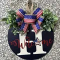 Detail showing the patriotic wooden door sign with a flag patterned bow and Welcome text. - Navy Blue Letter H Welcome Style