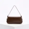 Bolso de hombro baguette minimalista color granate en un pedestal blanco geométrico moderno - Marrón Oscuro