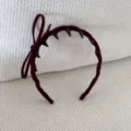Close-up of a stylish burgundy velvet headband featuring a side bow and black decorative spikes. - Bow Headband / Burgundy