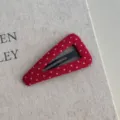 Rode stoffen haarklem met witte stippen op een luxe getextureerde crème achtergrond - Driehoek - Polka Dot Rode Haarspeld