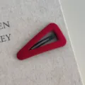 Gedetailleerde close-up van een rode fluwelen driehoekige haarklem op canvas achtergrond - Driehoek - Effen Kleur Rode Haarspeld