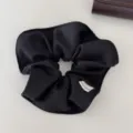 Primer plano de un coletero de tela negra texturizada con una etiqueta de hecho a mano - Negro