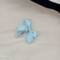 Vista dettagliata di un fermaglio per capelli con fiocco in raso azzurro su stoffa - Blu
