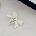 Dettaglio di un'elegante molletta per capelli con fiocco color crema su tessuto - Beige