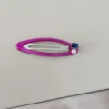Gros plan détaillé d'une pince à cheveux rose avec perle et détail en zircon bleu - Clips BB / Rose rouge