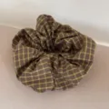 Detailansicht eines übergroßen karierten Haargummis mit lila und grünen Karos. - 3# Kaffee Karomuster