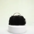 Elegant black ruffled tulle evening clutch with a gold handle on a display stand - Black