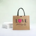Eco-friendly jute shopping tote bag featuring a pink heart and Love Yourself print design - LOVE Letter